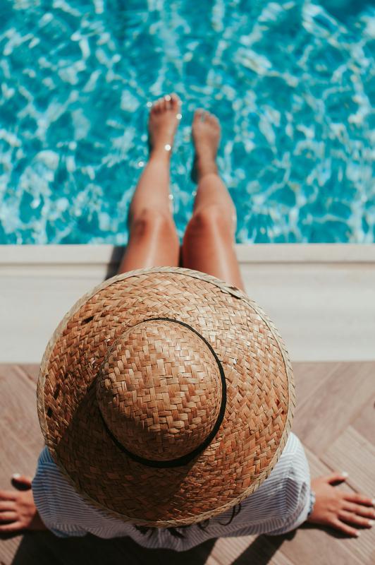 Frau mit Strohhut am Pool
