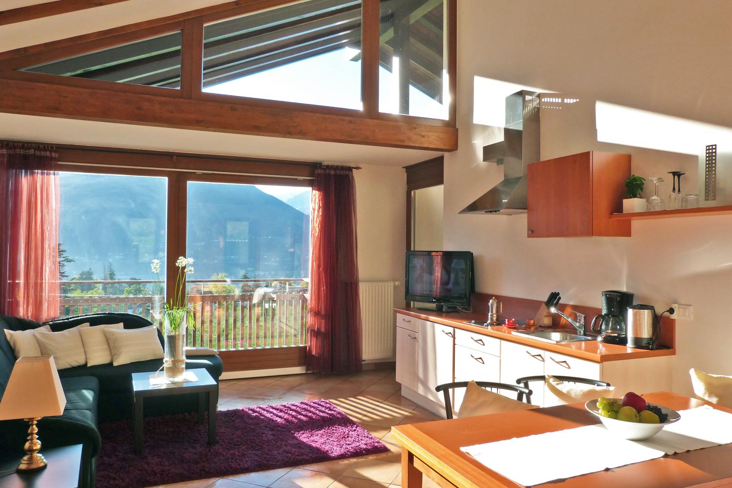 Wohnraum mit großen Fensterfronten und Küche – Maisonette Apartment